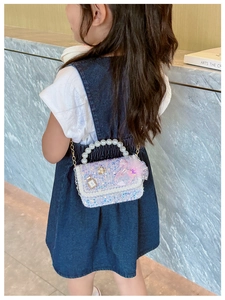 Close-up of girls' purple sequin bag with pearl handle and swan tulle decoration