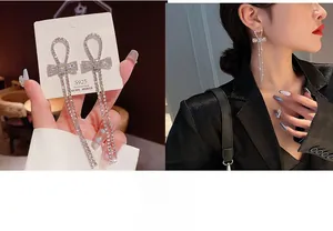 Detail of silver S925 needle bow earrings with long sparkling rhinestone tassels on model