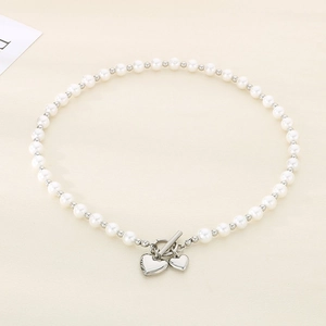 Detail of pearl necklace with OT clasp and silver heart pendants on beige background