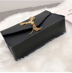 Detail of black faux leather bag with gold deer hardware and metallic tassel fringes