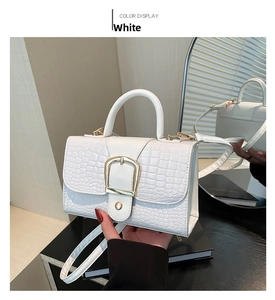 Détail du sac à main blanc motif crocodile avec une grande boucle en métal doré chic