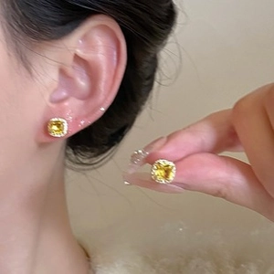 Détail de boucles d'oreilles carrées en pierre jaune et diamants sur base dorée