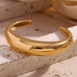 Detailed view of polished 18K gold plated minimalist open cuff bangle on stone texture