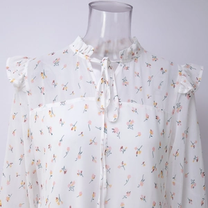 Dettaglio dello scollo con volant e laccetto regolabile sull'abito in chiffon a fiori bianchi