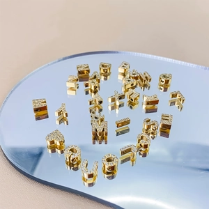 Detailed view of gold rhinestone letter pendants and heart charm on mirror surface