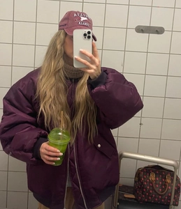Detail of oversized purple bomber jacket styled with an embroidered baseball cap