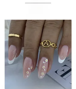 Detail of almond-shaped French nails with white flowers and heart patterns on nude pink base