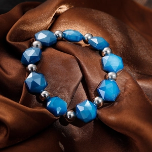 Close-up of blue faceted crystal beads and silver steel balls on brown satin fabric