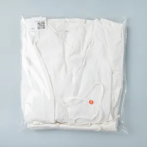 Folded white cotton-linen top with waist ties in transparent packaging bag