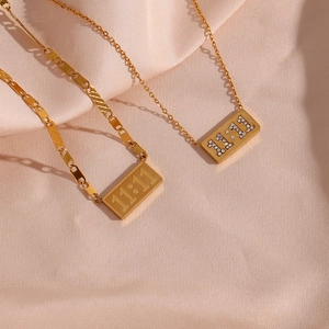 Macro shot of 11:11 gold rectangle pendants on pink silk, one plain and one with diamonds