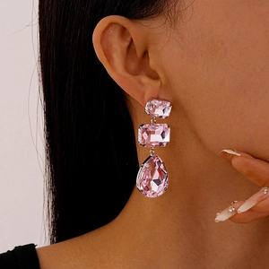 Dettaglio di orecchini lunghi con cristalli rosa quadrati e a goccia su una modella