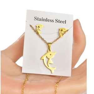 Golden dolphin necklace and earrings set in stainless steel on white jewelry card