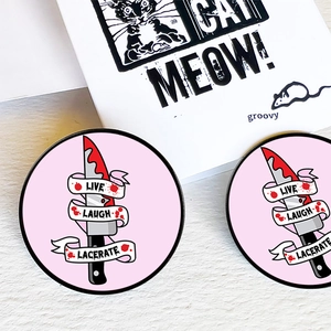 Close-up of pink Horror Movie Lover pins featuring a bloody dagger and gothic ribbon text