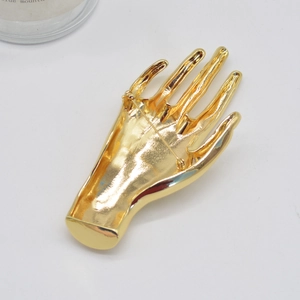 Detailed back view showing the pin fastening of a polished gold hand-shaped brooch