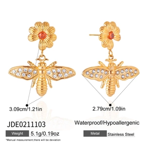 Vue détaillée des boucles d'oreilles abeille et fleur en acier doré avec pierres rouges
