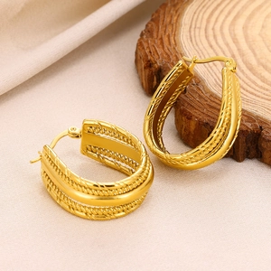 Macro shot of gold U-shaped twisted rope earrings on a natural wood and linen background