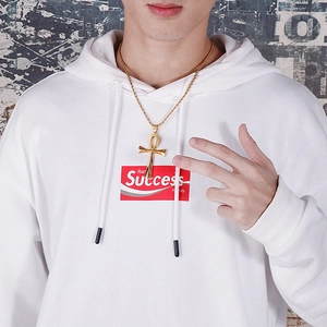 Close-up of golden Ankh cross pendant with twisted chain worn by a male model