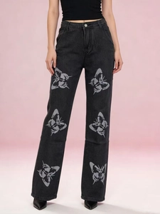 Vue détaillée des motifs papillon argentés sur un jean noir à taille haute droit