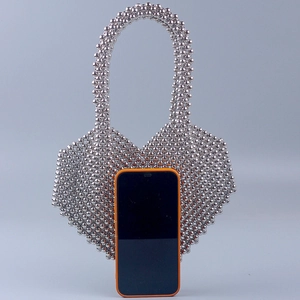 Dettaglio della borsa a mano in perle argentate a cuore con uno smartphone per riferimento