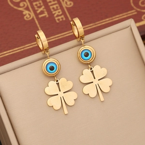Golden stainless steel clover earrings with blue evil eye beads on a jewelry box