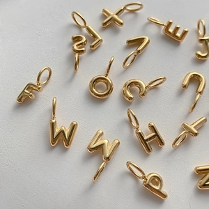 Detail of 14K gold plated bubble alphabet charms for DIY necklace and bracelet jewelry.