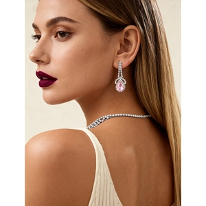 Detailed view of pink teardrop gemstone earrings and necklace set on female model