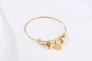 Detailed view of adjustable gold bangle with queen coin, heart and bead charms