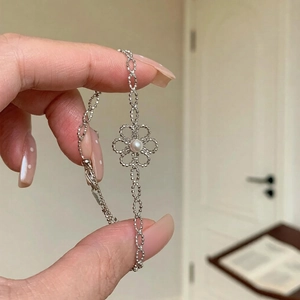 Vue détaillée du bracelet fleur évidée avec une perle blanche sur une chaîne argent
