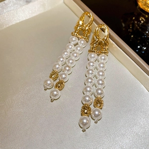 Detailed macro view of gold vintage relief studs with elegant double row pearl tassels