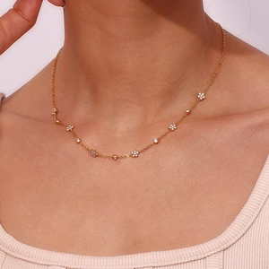 Close-up of golden necklace with delicate flower pendants and round zircon accents