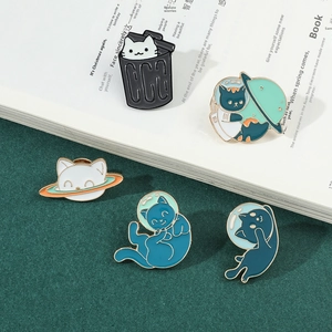 Detailed view of cute cartoon astronaut cat enamel pins on white book background