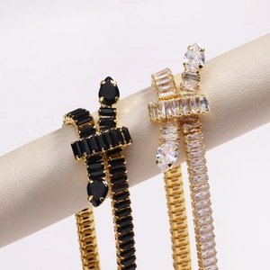 Detail of snake-shaped tennis bracelets with black and clear stones on gold plating