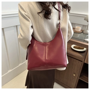 Detail of soft burgundy leather tote bag carried by a model in a bright cafe setting