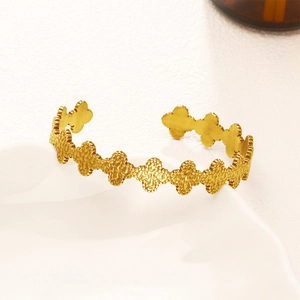 Bracciale rigido dorato con motivi a quadrifoglio e finitura martellata per donna