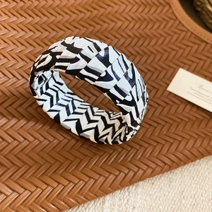 Detailed view of wide woven black and white zebra pattern bracelet on textured surface