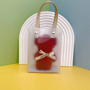 Detailed view of red plush bear with pearl pendant in a transparent PVC gift bag