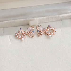 Macro shot of rose gold butterfly earrings with pearls and colorful zircons on velvet