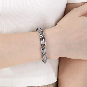 Close-up of a silver stainless steel square-line spring bracelet worn on a wrist