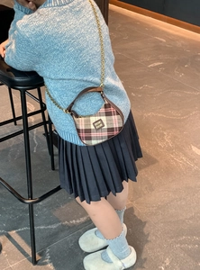 Détail du sac demi-lune à carreaux roses avec chaîne dorée et poignée en cuir