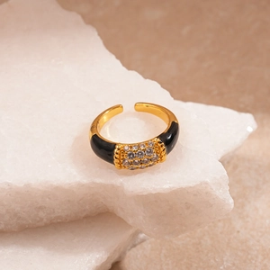 Macro shot of geometric gold ring with black enamel and zircons on stone pedestal
