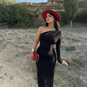 Detailaufnahme des schwarzen One-Shoulder-Kleides mit elegantem Faltenwurf in der Natur
