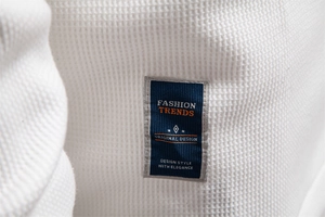 Detail of white waffle texture fabric with blue fashion label and quality stitching