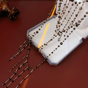 Detail of layered black faceted beads and gold metal tubes draped over a jewelry box