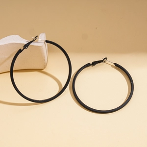 Minimalist matte black geometric round hoop earrings on a decorative stone display