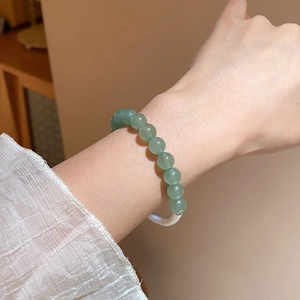 Detail of green aventurine beaded bracelet with silver metal clasp on female wrist