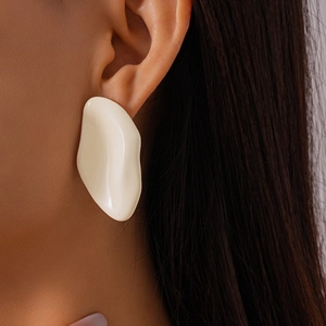 Close-up of white irregular geometric oval stud earring with glossy finish on model