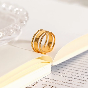 Close-up of 18k gold-plated stainless steel ring with braided textures on a book
