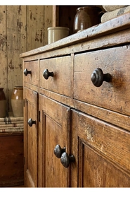 Close-up of vintage cast iron knob on a rustic dark wood cabinet with drawer detail