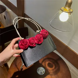 Detail of black satin evening bag with red 3D roses and elegant double pearl handle