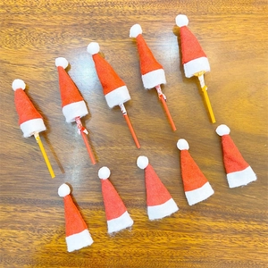 Mini Christmas lollipop hats, small red and white felt ornaments on wooden background